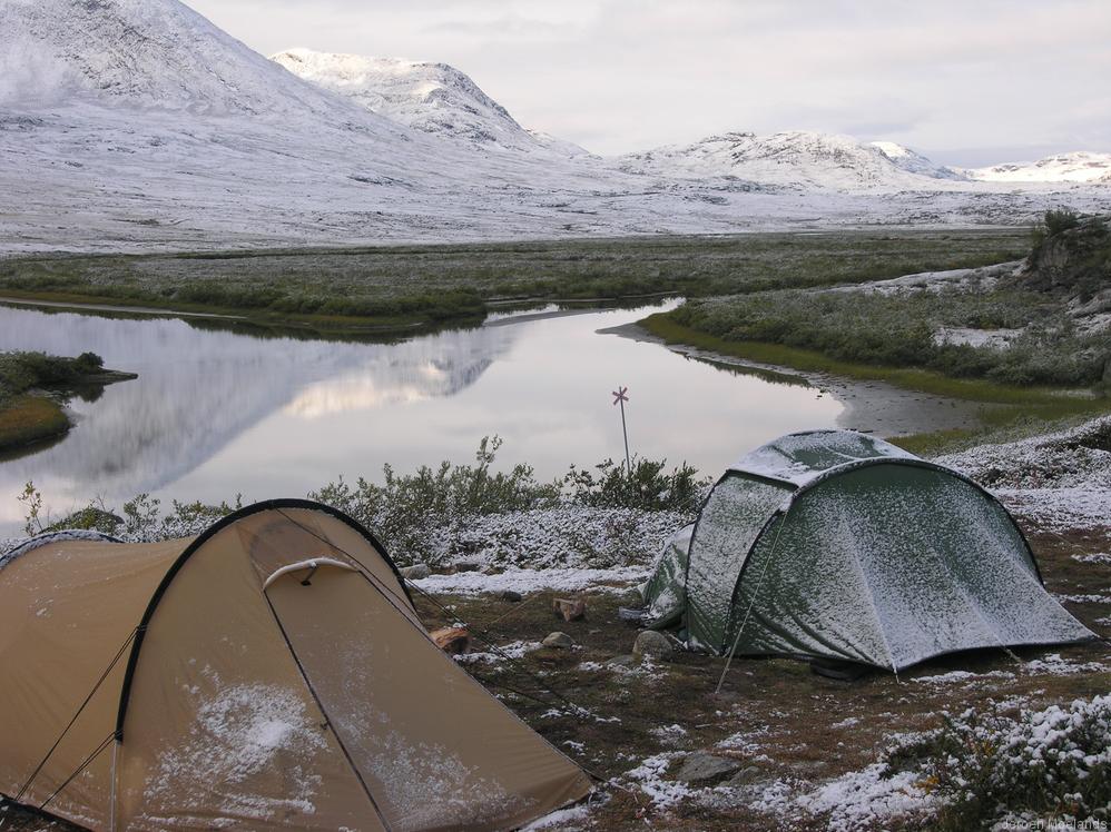 Heel vroeg in de ochtend op de kampeerstek onder de hut Abiskojaure. Een nachtelijke sneeuwbui heeft het landschap en de tenten bedekt met een laagje poedersuiker. - Kungsleden wandelpad - Wandelen in Lapland - Wandelen in Zweden - Jeroen Moelands